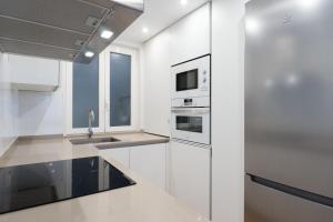 a white kitchen with a sink and a microwave at Arrasate Center - Iberorent Apartments in San Sebastián