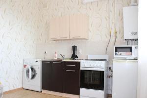 a kitchen with a stove and a washer and dryer at Уютная двушка in Elista