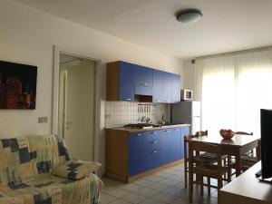 cocina y sala de estar con armarios azules y sofá en Appartamenti Aquamarina en Lido di Jesolo