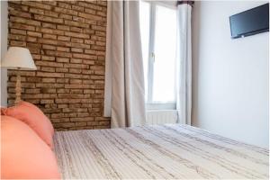 ログローニョにあるApartamento en Casco Antiguoのレンガの壁とベッド、窓が備わるベッドルーム1室が備わります。