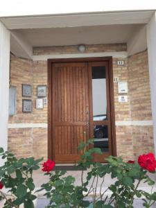 a wooden door on a brick building with red roses at Itaka in LʼAquila