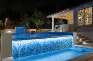 una piscina por la noche con azulejos azules en Apartments Rafaj, en Pula