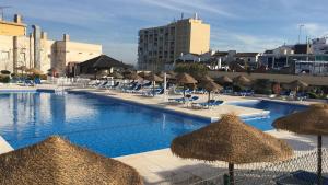a large swimming pool with chairs and umbrellas at Nogalera Beach Apartment in Torremolinos