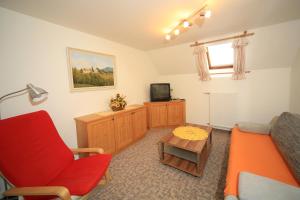 ein Wohnzimmer mit einem roten Stuhl und einem Sofa in der Unterkunft Kniebergerhof in Liebenfels