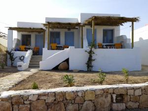 a house with white walls and a stone wall at Ammos Studio in Koufonisia