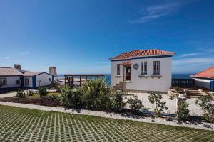a small white house with the ocean in the background at Chalet O Amorzinho Sintra Praia in Sintra
