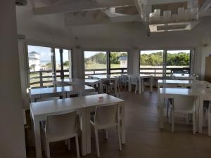 een restaurant met witte tafels, stoelen en ramen bij Apart en la Playa Mar de las Pampas in Mar de las Pampas