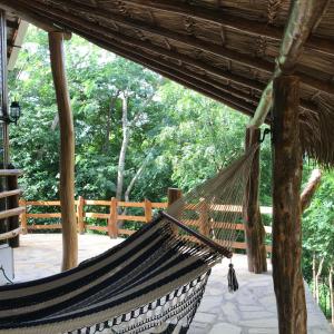 a hammock in a building with trees in the background at NuestraMadreTierra in La Esperanza