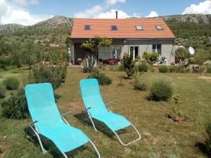 deux chaises bleues assises dans l'herbe devant une maison dans l'établissement B&B Curica Doma, à Šibenik