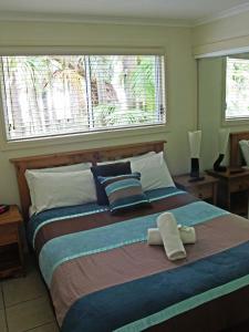 a bedroom with a large bed with two towels on it at The Palms At Avoca in Avoca Beach