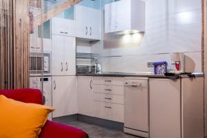 a kitchen with white cabinets and a red couch at TANTRA Love SPA in Lancharejo