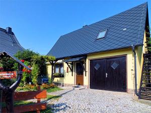 une maison avec un toit noir et un garage dans l'établissement FH Schmidt, à Hohnstein