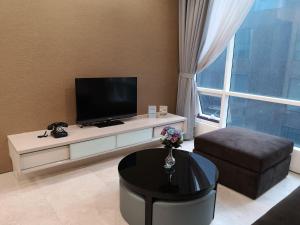 a living room with a flat screen tv and a table at Soho Suites Klcc By Pnut in Kuala Lumpur