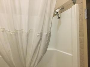 a shower curtain with a white shower curtain at Ramada by Wyndham Pincher Creek in Pincher Creek