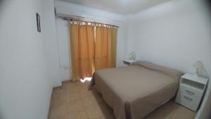 1 dormitorio con cama y cortina de color naranja en Departamento en pleno centro de San Juan en San Juan