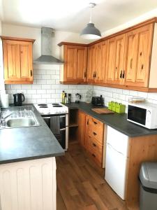 een keuken met houten kasten en zwarte aanrechtbladen bij Castleton townhouse in Belfast