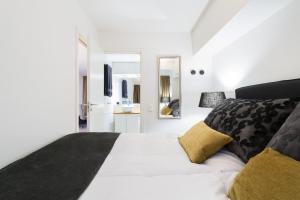 Un dormitorio con una gran cama blanca con almohadas negras y amarillas en Nordic Host - Prinsens Gate 10 city center - High-end, en Oslo