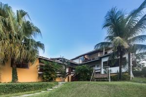 a house with palm trees in front of it at Aloha Buzios in Búzios