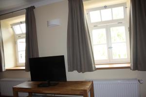 Zimmer mit 2 Fenstern und einem Schreibtisch mit einem TV in der Unterkunft Landhaus Hui Wäller in Beilstein
