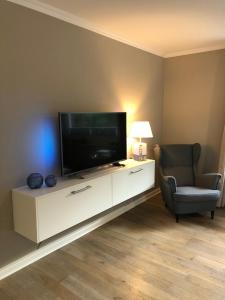 a living room with a flat screen tv and a chair at Strandgut 63 in Scharbeutz