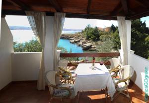 a table and chairs on a porch with a view of the water at Ribarica GO green in Ribarica