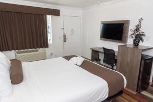 a hotel room with a bed and a desk and a television at Value Inn Bellflower in Bellflower