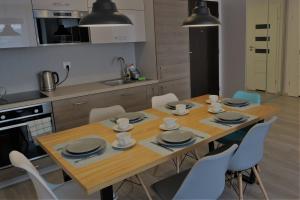 a kitchen with a wooden table and blue chairs at Blue Sea Apartment in Kołobrzeg