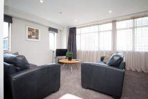 a living room with two leather couches and a table at Quest on Johnston Serviced Apartments in Wellington