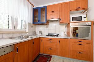 a kitchen with wooden cabinets and a sink and a microwave at Holiday home VesnaD-25m from beach in Seget Vranjica