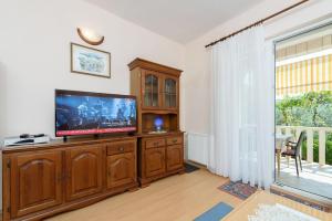 a living room with a flat screen tv on a wooden entertainment center at Holiday home VesnaD-25m from beach in Seget Vranjica
