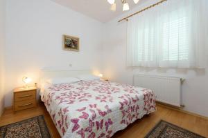 a white bedroom with a bed and a window at Holiday home VesnaD-25m from beach in Seget Vranjica