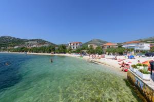 a beach with a group of people in the water at Holiday home VesnaD-25m from beach in Seget Vranjica