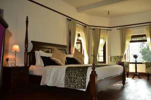 a bedroom with a large bed with white sheets and pillows at Hill Cottage in Nuwara Eliya