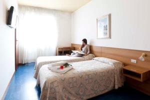 a woman sitting on a bed in a hotel room at Hotel Dante in Ponte nellʼAlpi