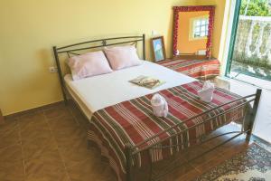 a bed with pink pillows and a mirror in a room at Modern flat with beautiful views in south of Corfu in Lefkímmi