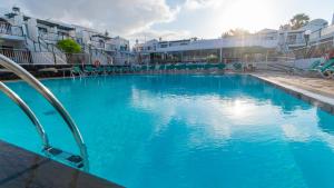 niebieski basen z krzesłami i budynkami w obiekcie Bitacora Lanzarote Club w Puerto del Carmen