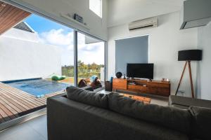 un salon avec un canapé et une piscine dans l'établissement Aurelia Residence, à Uluwatu