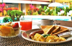 a plate of breakfast food on a table with a drink at Hotel Puerta del Sol - San Jose Airport in San José