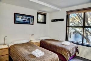 two beds in a room with a window at Boali Lodge Thredbo in Thredbo