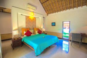 a bedroom with a bed with a blue comforter at Blind Dog Inn in Sanur