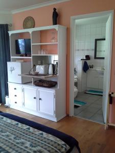 Habitación con cocina con armario blanco en The Little Gem en Waitara