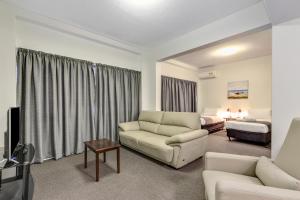 sala de estar con sofá y cama en Rockhampton Riverside Central Hotel Official en Rockhampton