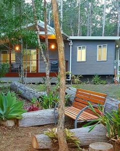 Gheerulla的住宿－奧基溪私人休閒公寓，坐在房子前面的木凳