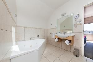 a white bathroom with a tub and a sink at Voyager Apartments Taupo in Taupo