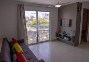 sala de estar con sofá, TV y balcón en Flat Esmeralda, en Natal