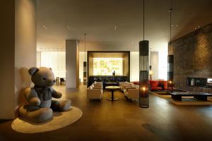 a teddy bear sitting on a rug in a room at Shilla Stay Jeju Airport in Jeju