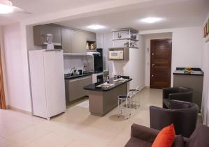 a kitchen with a refrigerator and chairs in a room at Flat Esmeralda in Natal