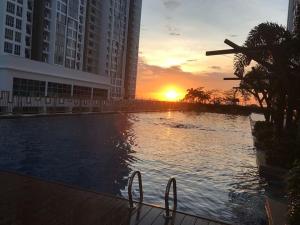 a sunset over a swimming pool in a city at Meridin Bayvue Serviced Apt in Kampong Kuala Masai