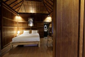 a bedroom with a bed and a table in a room at Jungle Joglo in Tampaksiring
