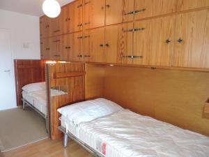 a bedroom with two beds and wooden cabinets at Astoria (175 Cl) in Lenzerheide